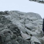 A man standing on a rock in the snow.