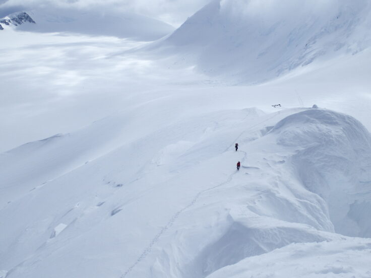 A man riding a snowboard down a snow covered mountain