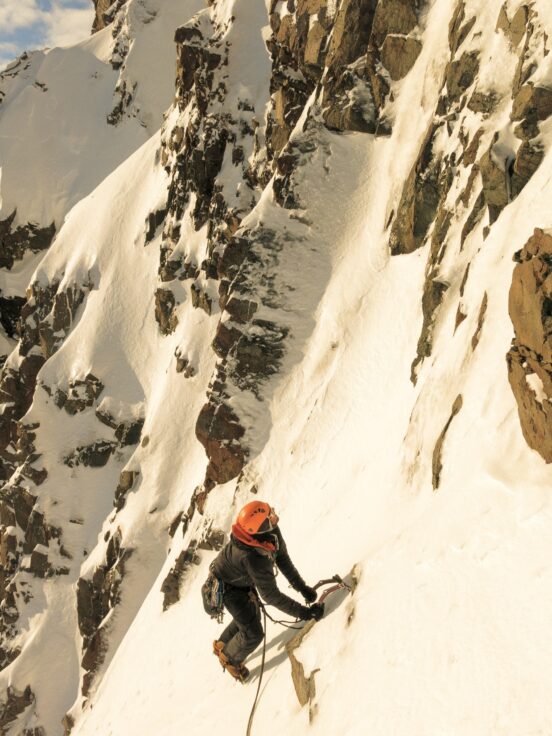 A man riding skis down the side of a snow covered slope