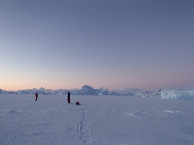 A group of people walking up a hill in the snow