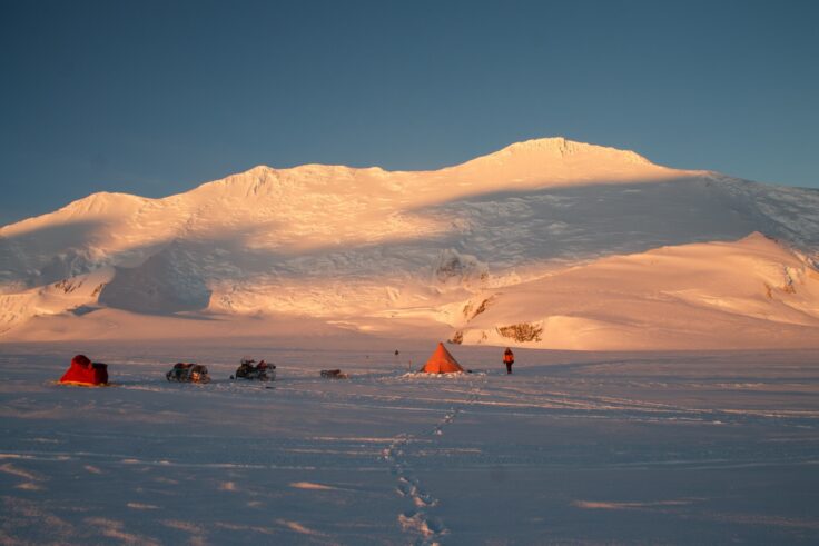 A group of people on a beach with a mountain in the background