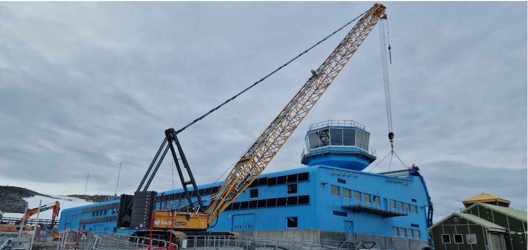 A large bright blue building with a yellow crane
