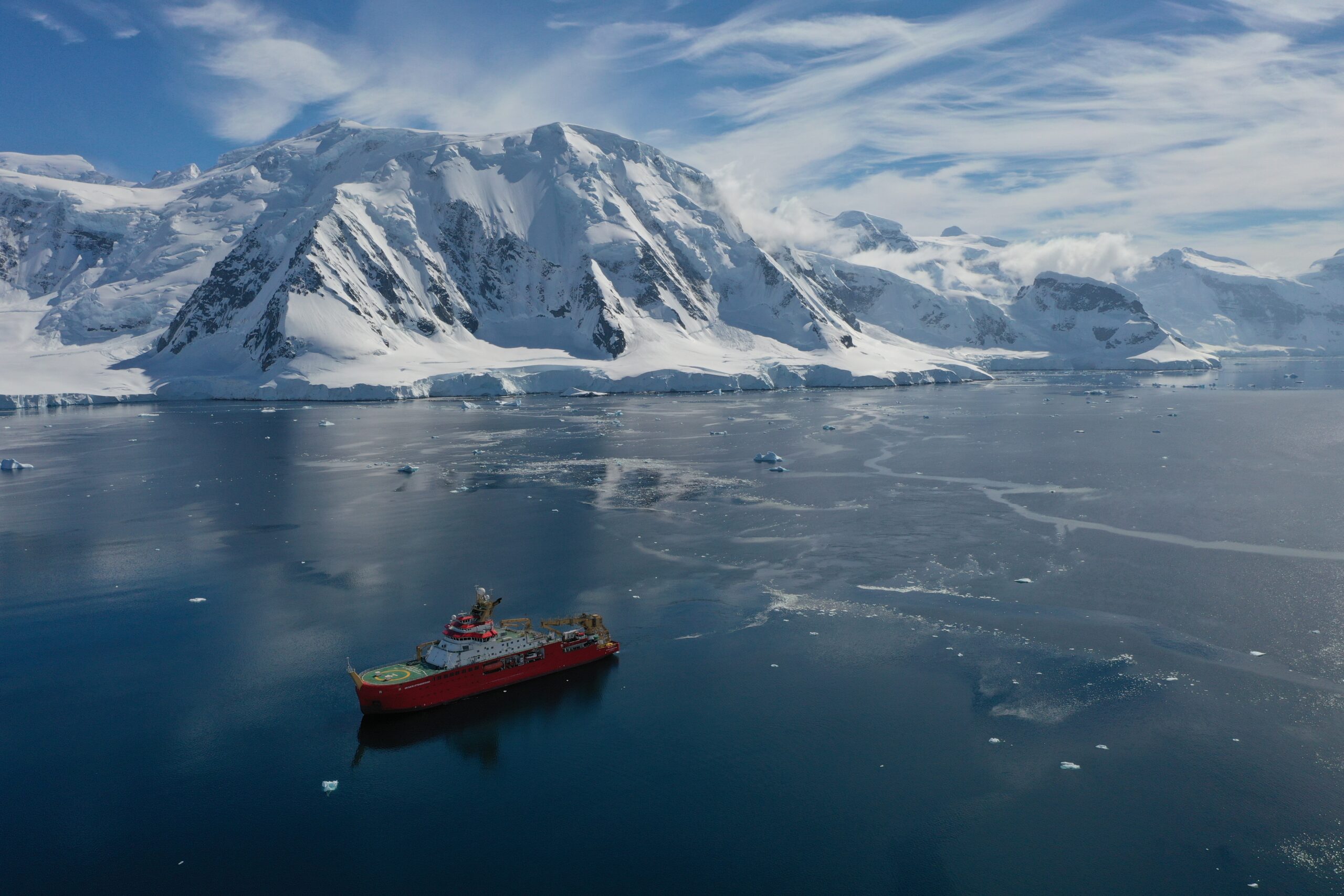 A ship in a Greenlandic fjord with a snow-capped mountain behind