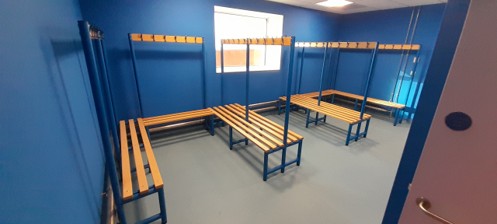 A large empty room with wooden benches and coat hangers